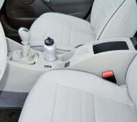 V robustní konzole mezi sedadly jsou před schránkou pod výklopnou loketní opěrkou páčka parkovací brzdy, hlavní spínač tempomatu a dvě dutiny pro nádobky