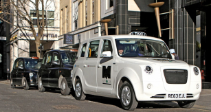 Bílý Metrocab REE na stanovišti spolu s klasickými černými typy LTI RX4 