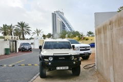 Typický vozový park během polední přestávky před vilkami u pláže, v pozadí hotel Jumeirah Dubai