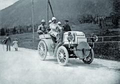 Emil Jellinek za řídítky vozu Daimler Phoenix s čtyřválcovým motorem o maximálním výkonu 24 k na Semmeringu v roce 1899. Vedle něj sedí na sedadle spolujezdce Hermann Braun – mechanik od Daimlerů. Vzadu, zleva doprava: Ferdinand Spiegel, Otto H. Zels a Fernand Jellinek.