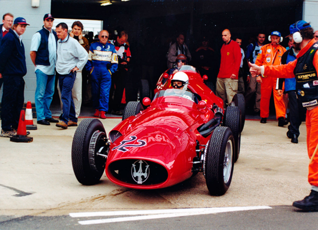 Stirling Moss (Maserati 250F) vyjíždí před někdejším soupeřem Tonym Brooksem (Ferrari 500) na trať při závodech veteránů v Silverstone (2000)