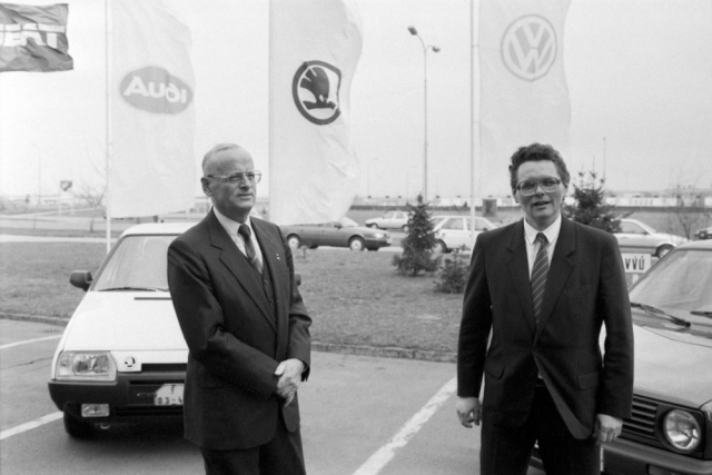 28. března 1991. Carl Hahn, předseda představenstva Volkswagen AG, a Petr Dědek, od roku 1987 podnikový ředitel AZNP, následně ředitel státního automobilového koncernu Škoda, po 16. 4. 1991 ředitel zbytkového státního podniku, který byl pak přejmenován na STASKO (Státní, případně Stará Škoda). Prof. Hahn symbolicky stojí před vozem Škoda Favorit a Petr Dědek před Volkswagenem Golf