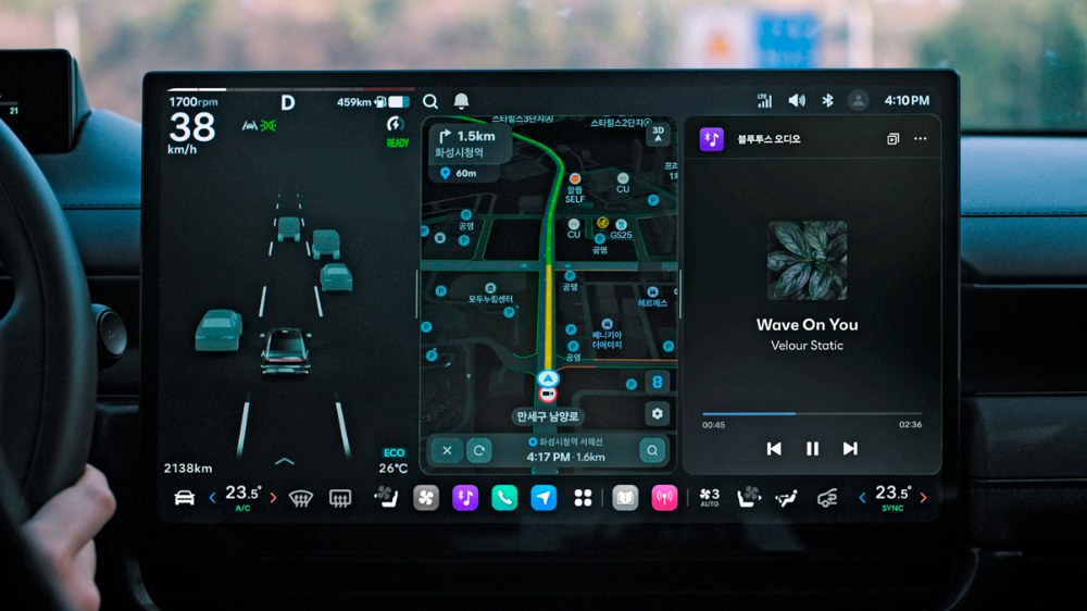 Středový dotykový displej systému Pleos Connect. Údaje o řízení vlevo vizualizují okolní objekty a jízdní pruhy, zatímco část aplikací zobrazuje navigaci a Bluetooth audio v režimu rozdělené obrazovky