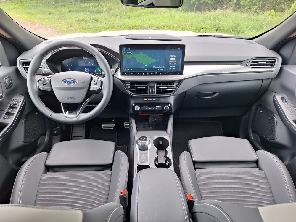 Pracoviště řidiče ve voze Ford Kuga zůstává i po šesti letech vzorem příkladné ergonomie a jednoduchosti. ­S­amozřejmostí je skvělý volant s tlustým věncem a velkými mechanickými přepínači na jeho ramenech. O módním otočném voliči převodovky nechť si myslí každý, co chce…